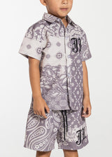 This is a boy wearing the Haus Of Jr Button up shirtAngel Button Up perfect for out in the sun and in the water  Mauve Paisley Button Up Snap Down Buttons Polyester Fabric Embroidered JR Logo Front Chest